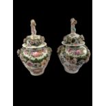 A pair of 19th century Continental floral encrusted and hand painted lidded urns with cherub