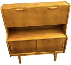A teak mid century drinks cabinet, with two fall front cupboards enclosing fitted interior above