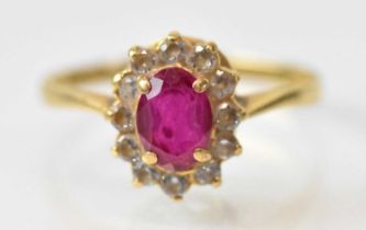 An 18ct yellow gold ruby and diamond set cluster ring, the central ruby approx 0.75ct, surrounded by