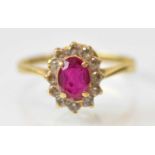 An 18ct yellow gold ruby and diamond set cluster ring, the central ruby approx 0.75ct, surrounded by
