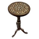 An Islamic tripod table inlaid with mother of pearl and bone, height 71cm, diameter 32cm.