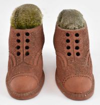 A E MERRIFIELD; a pair of terracotta pin cushions modelled as boots, signed and dated to the base '