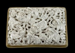 A Chinese porcelain belt buckle, panel moulded and pierced with Buddhist lions, 8 x 5cm.