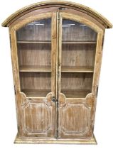 A large modern limed oak two door display cabinet, with a domed top and an arrangement of four