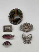 Six white metal and silver brooches including one decorated with the Golden Dog of Quebec, a