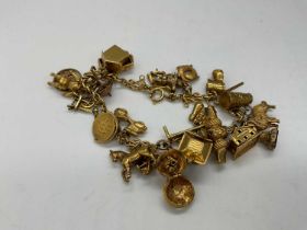 A 9ct yellow gold charm bracelet with numerous charms, including a whistle, clown and dog, approx