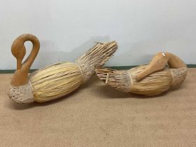 A pair of thatched and carved wooden swans, largest height 52cm, length 79cm.