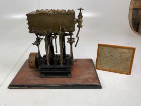 A scratch built scale model twin cylinder marine engine mounted on a wooden base, with