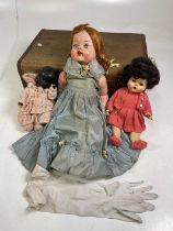 Three various vintage dolls in a vintage suitcase.