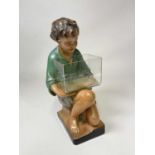 A large chalk plaster painted figure of a kneeling boy holding a glass fish tank, impressed mark