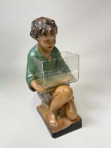 A large chalk plaster painted figure of a kneeling boy holding a glass fish tank, impressed mark