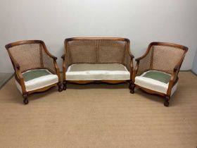An Edwardian three piece stained beech Bergère caned suite, raised on ball and claw supports and