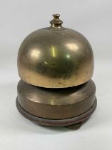 An unusual large domed brass bell with brass lower section and raised above a wooden frame on