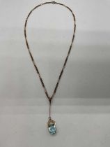 A yellow metal fine link chain suspending a aquamarine coloured pendant drop, length of chain