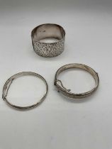 A broad silver bangle with leaf engraved detail and two narrower examples, combined approx 66g.