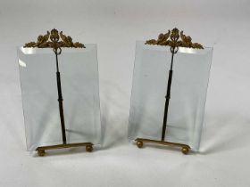 A pair of French glass and gilded metal photo frames styled as easels with winged lion and floral