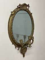 An oval gilt gesso mirror with decorative beaded edge and triple stemmed girandole base. Condition