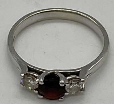 A 9ct white gold garnet and diamond three stone ring, size P, 2.7g