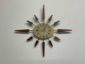 MANLEY; a mid 20th century quartz atomic starburst wall clock with teak decorative finials,