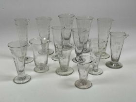 Thirteen engraved and handblown 19th century conical apothecary glass measuring cups, tallest 17cm.