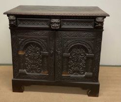 An oak side cabinet, with a single drawer above two carved doors, enclosing three graduating