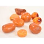 A group of loose egg yolk/butterscotch amber beads, the largest approx 33 x 30mm, also two pendants,