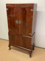 A mahogany cocktail cabinet with twin cupboard doors to both upper and lower sections, mirrored