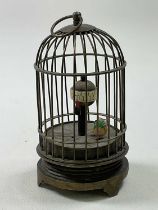 An early 20th century novelty single bird timepiece in the form of a cage with automaton ticking