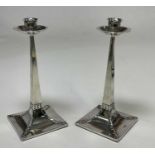 JAMES DIXON & SONS; a pair of Edwardian hallmarked silver Arts and Crafts candlesticks, the design