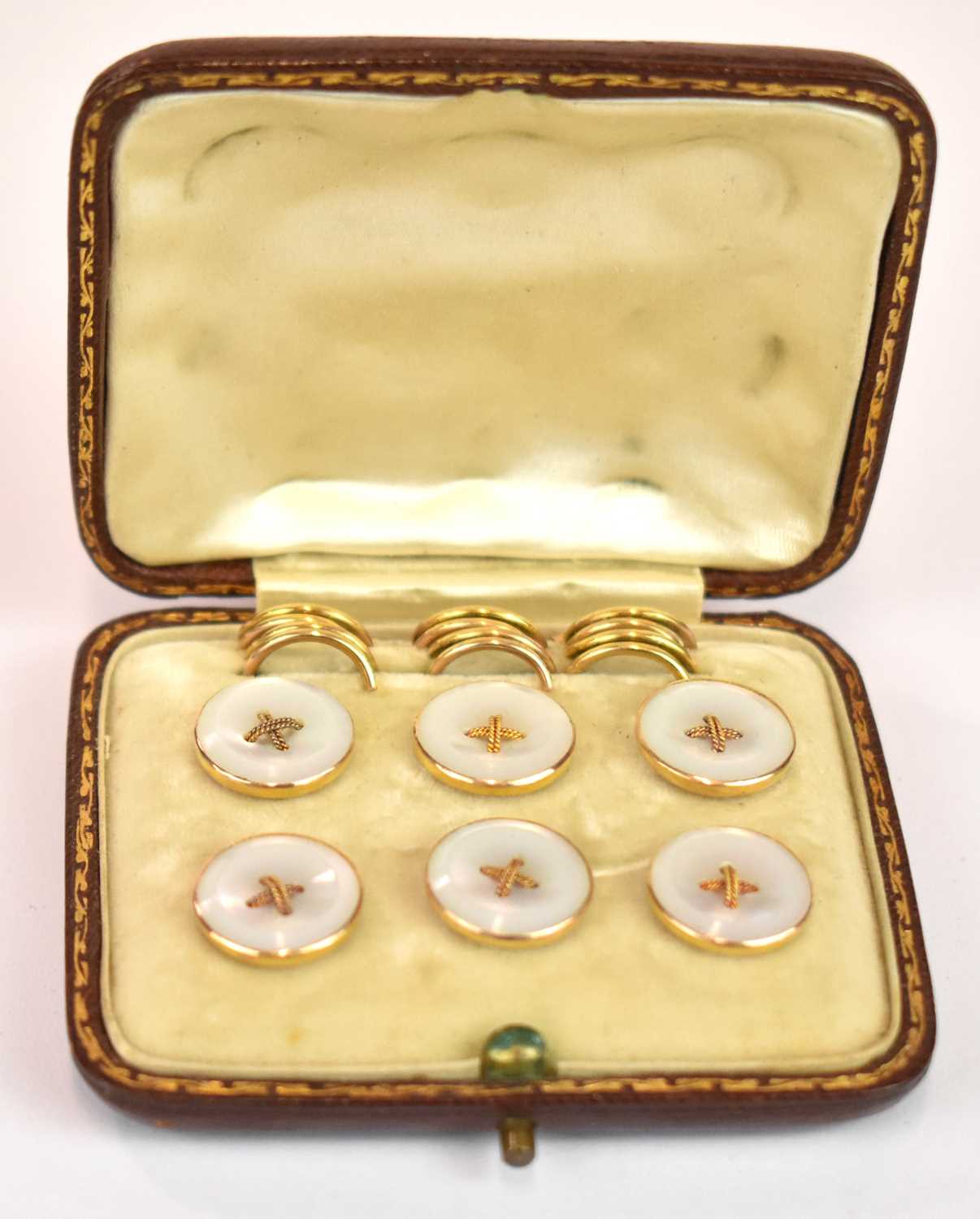 A cased set of six Edwardian 15ct yellow gold button studs with mother of pearl faces, complete with