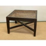 A 19th century square ebonised table with cross band supports and rattan top, height 41cm, width