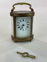 A circa 1900 French oval brass carriage clock with Roman numerals to the white enamel dial, with