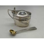 An Edwardian hallmarked silver lidded mustard with blue glass liner and associated silver spoon, the