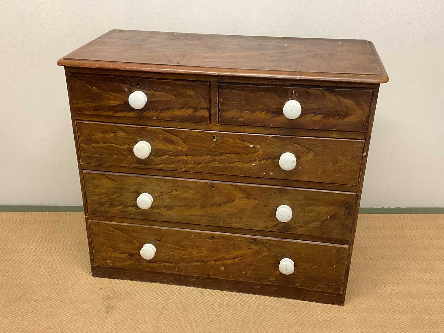 A 19th century scumbled pine chest of drawers, with two short and three long drawers, with ceramic