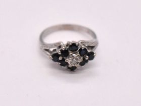 An 18ct white gold sapphire and diamond cluster ring with lozenge shaped claw set platform, size J