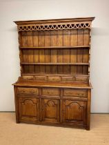 An oak dresser, the upper section having a panelled back and a three shelf plate rack above a base