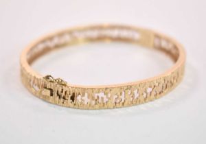 A 9ct yellow gold textured and pierced oval hinged snap bangle, internal width 60mm, approx. 16.2g.