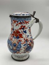 An 18th century Chinese tankard with white metal mounts, hinged lid, bellied body and spreading