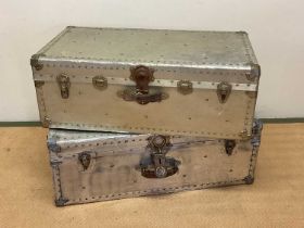 Two aluminium travelling trunks with rivet detailing, larger height 33cm, width 91cm, depth 50cm.