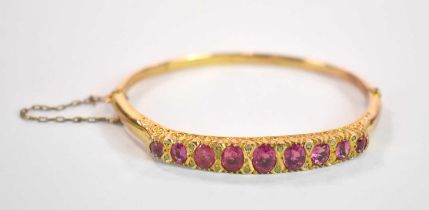 A late Edwardian 9ct yellow gold morganite and diamond chip hinged oval snap bangle with scroll