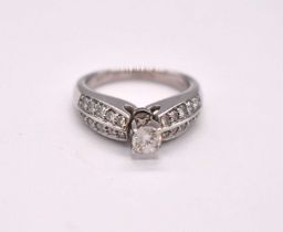 A 14ct white gold diamond cluster ring, the four claw set round brilliant cut central stone and