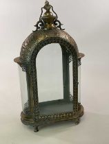 A decorative lantern in distressed grey and gold metal with filigree style detail and curved glass