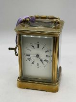 A circa 1900 French brass carriage clock with Roman numerals to the white enamel dial, case door