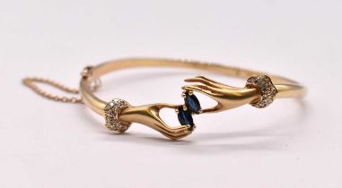 An Italian 14ct yellow gold sapphire and diamond set bangle modelled as two hands touching with