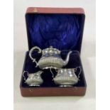 X MARTIN, HALL & CO; a cased George V hallmarked silver three piece tea set with part gadrooned