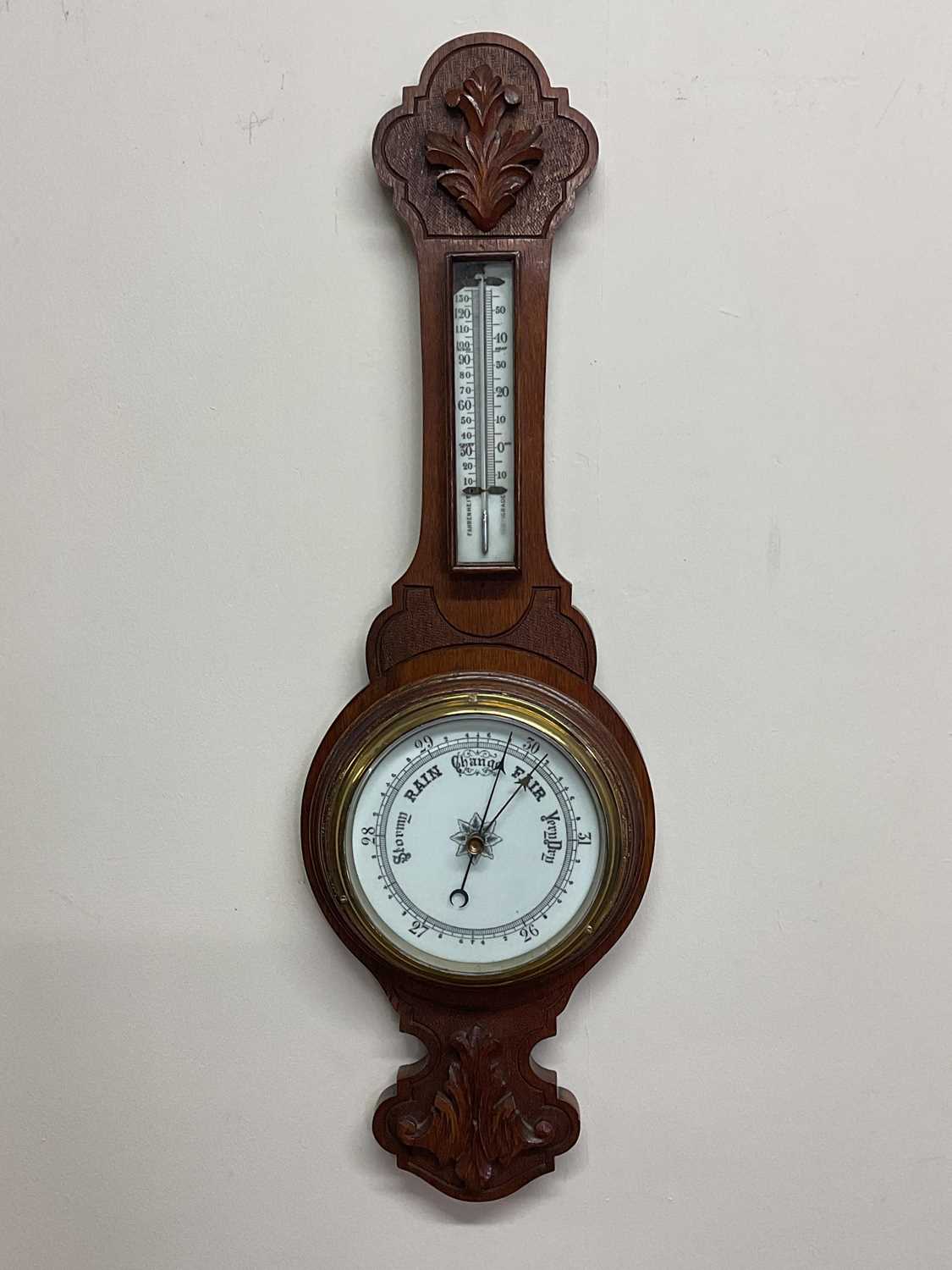 A carved oak barometer with porcelain dial and scale, length 71cm.