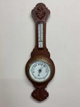 A carved oak barometer with porcelain dial and scale, length 71cm.