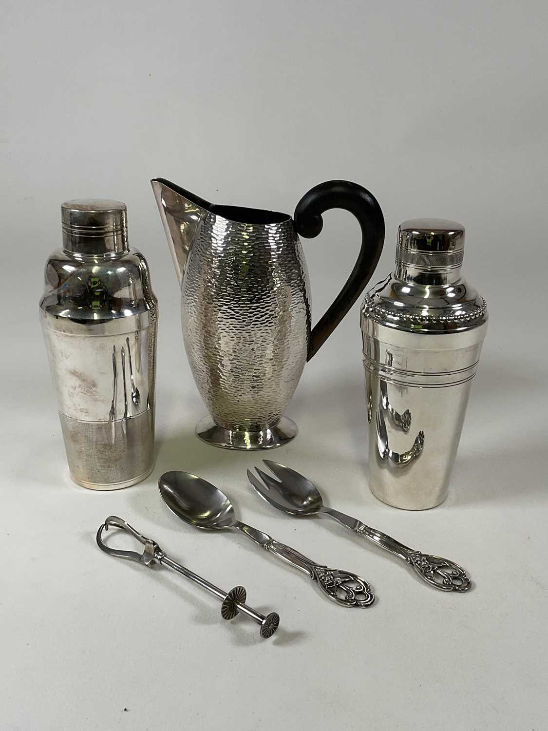 Two silver plated cocktail shakers, a stylish silver plated jug with ebonised handle and textured