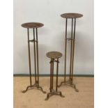 Three Art Nouveau adjustable brass shop display stands, raised on three splayed supports, tallest