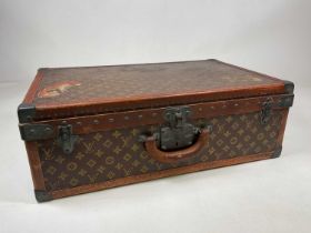 LOUIS VUITTON; a rare early 20th century monogrammed suitcase with applied corners and remnants of